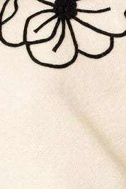 Flower Embroidery Mock Neck Sweater. white knit sweater with large black embroidered flowers.