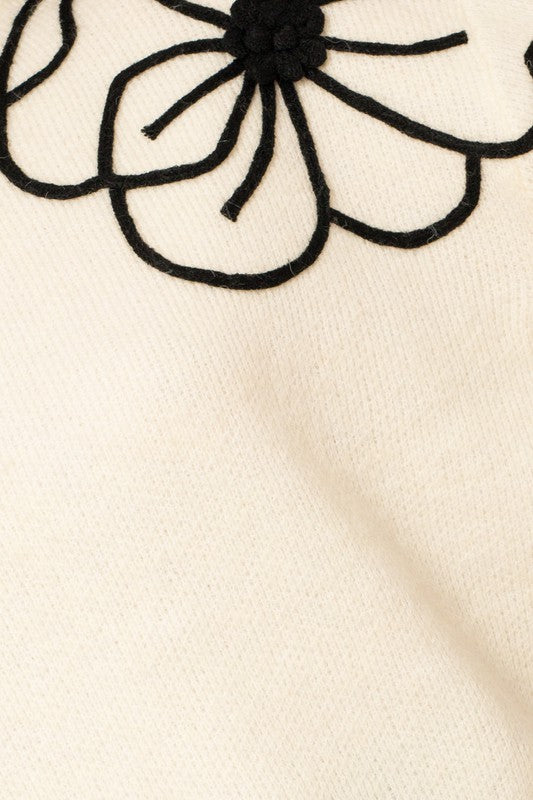 Flower Embroidery Mock Neck Sweater. white knit sweater with large black embroidered flowers.