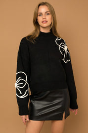 Flower Embroidery Mock Neck Sweater. Black knit sweater with large white embroidered flowers.
