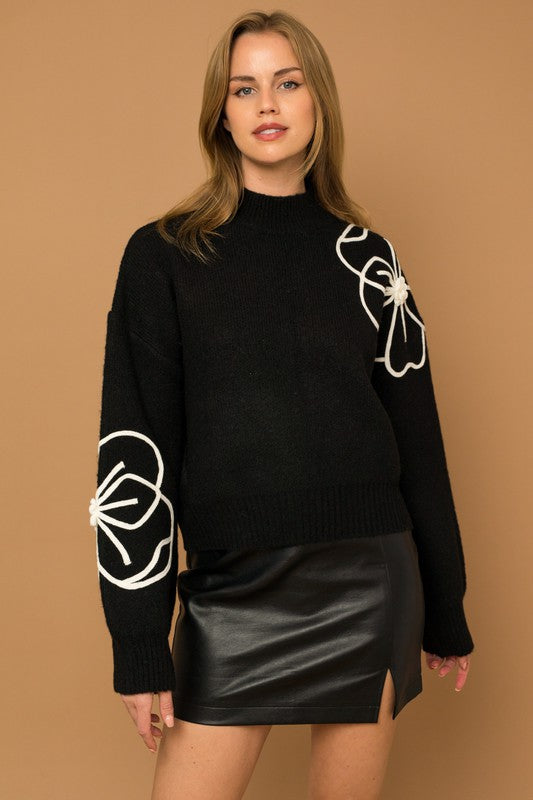 Flower Embroidery Mock Neck Sweater. Black knit sweater with large white embroidered flowers.
