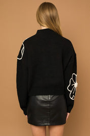 Flower Embroidery Mock Neck Sweater. Black knit sweater with large white embroidered flowers.