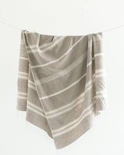 Ethically crafted in Ethiopia. Cotton throw blanket. Measures 38 x 72 inches.  stone with natural. 